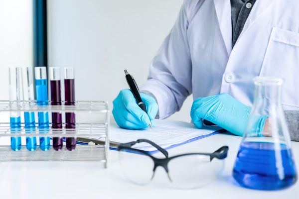 Biochemistry laboratory research, Chemist is analyzing sample and record in laboratory with equipment and science experiments glassware containing chemical liquid.